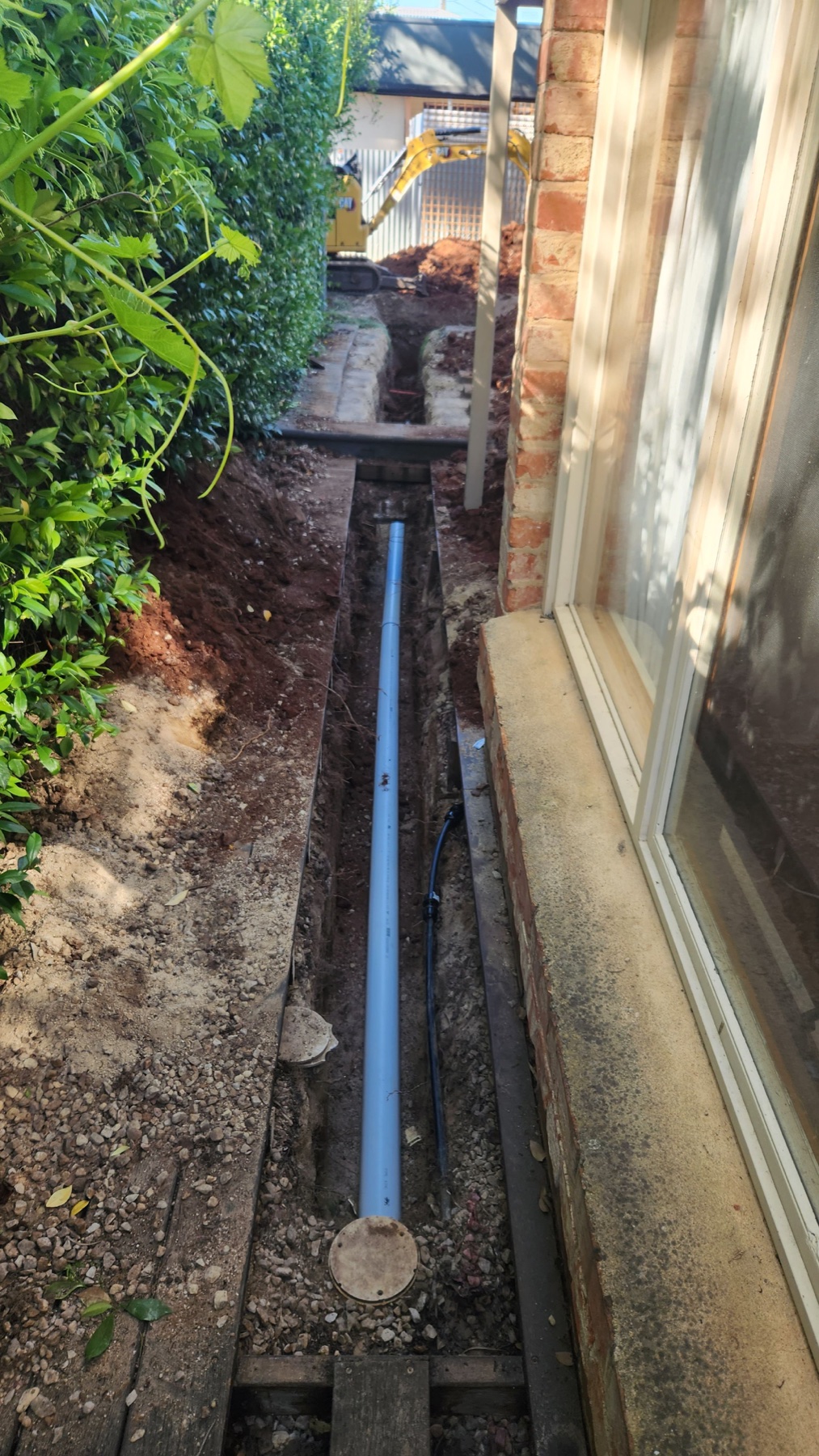 New drainage pipe installed in an external trench beside a home