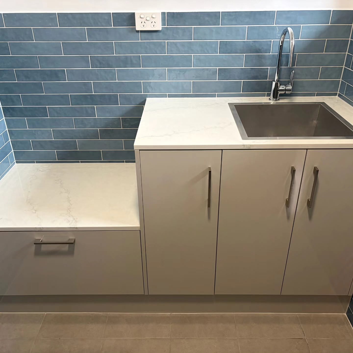 Laundry cabinetry, stainless-steel sink and blue tiled splashback