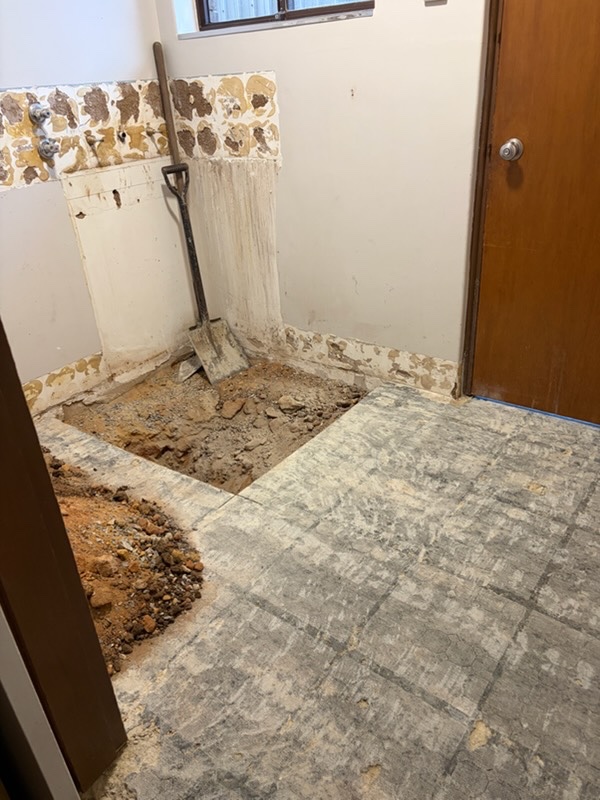 Laundry midway through renovation with the original finishes removed and floor opened for plumbing work