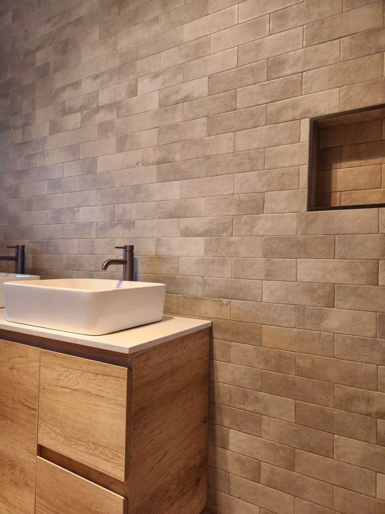 Timber vanity against a warm-toned tiled wall with recessed niche
